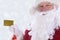 Closeup of Santa Claus holding his personal Noth Pole Gold Credit Card, with Winter Snow flakes on a silver background