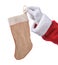 Closeup of Santa Claus holding a rustic burlap Christmas stocking in his fingers