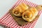 Closeup sausage baked in dough on wooden plate.