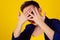 Closeup scared woman covering face with hands hiding face looking peering peeking through fingers on yellow background. Family