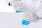 Closeup of a scientist experimenting with blue toxic substances in containers in a laboratory