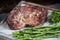 Closeup of the seasoned steak on a tray with greens on a blurry background