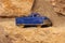 Closeup selective focus shot of a blue car toy on the edge of a sandstone