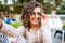 Closeup selfie-portrait student of attractive girl in sunglasses with curly hairstyle and snow-white smile in city.