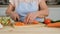 Closeup of Senior Woman Cuts Carrots in Kitchen