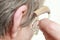 Closeup senior woman using hearing aid