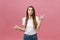 Closeup of serious strict young woman wears white shirt looks stressed and pointing up with finger isolated over pink