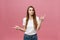 Closeup of serious strict young woman wears white shirt looks stressed and pointing up with finger isolated over pink