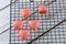 Closeup of several white chocolates tinted with pink paint, on a black railing with copy space