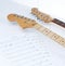 Closeup .sheet music and guitar on a white background.