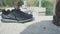 Closeup of shoes on background of barefoot person. Stock. Man took off his shoes and went to water barefoot. Hot summer