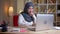 Closeup shoot of adult muslim successful female employee typing on the laptop looking at camera and smiling happily on