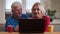 Closeup shoot of aged happy couple using the laptop with cups with tea on the desk indoors in a cozy apartment