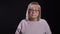 Closeup shoot of old caucasian blonde female in glasses being sad and depressed in front of the camera with background