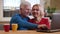 Closeup shoot of senior happy couple using the laptop on the desk with cups with tea smiling happily indoors in a cozy