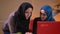 Closeup shoot of three young successful muslim businesswomen in hijabs working on the laptops. Two of them discussing a