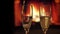 Closeup shoot of two empty glasses being poured a champagne into with cozy warm fireplace with flames on the background