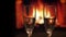 Closeup shoot of two empty wine glasses with cozy warm fireplace with flames on the background indoors in a dark