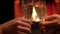 Closeup shoot of two hands clinking glasses full of champagne celebrating a night date with cozy warm fireplace with