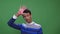 Closeup shoot of young attractive indian male waving hi looking at camera with background isolated on green