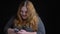 Closeup shoot of young overweight cheerful caucasian female texting on the phone and playfully smiling with background