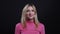 Closeup shoot of young pretty blonde female in a pink sweater smiling and being cute looking at camera with background