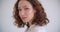 Closeup shoot of young pretty curly caucasian female smiling happily fixing her hair looking at camera with background