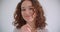 Closeup shoot of young pretty long haired curly caucasian female smiling happily posing in front of the camera with