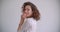 Closeup shoot of young stylish long haired curly caucasian female tossing hair smiling happily looking at camera with