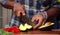 Closeup shot of an African-American man`s hands cutting an avocado with a big sharp knife