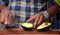 Closeup shot of an African-American man`s hands cutting an avocado with a big sharp knife