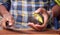 Closeup shot of an African-American man`s hands cutting an avocado with a big sharp knife