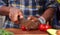 Closeup shot of an African-American man`s hands cutting a tomato with a big sharp knife