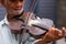 Closeup shot of an aged musician with wrinkled unshaven face playing the violin wonderful melody being on the street.