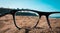 Closeup shot of beach viewed from the lenses of black glasses