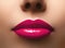 Closeup shot of beautiful full lips with magenta glossy make-up. Perfect bright pink lipstick. Plastic surgery