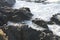 Closeup shot of a beautiful rocky coast of the ocean with white waved water