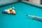 Closeup shot of billiard balls on a pool table with a cue stick