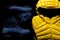 Closeup shot of blue winter trekking boots and a yellow down jacket on black background
