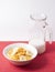 Closeup shot of a bowl of cornflakes and banana and a pitcher of milk