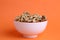 Closeup shot of a bowl of walnuts on an orange background