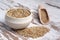 Closeup shot of a bowl and a wooden scoop of dried buckwheat on a wooden surface