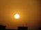 Closeup shot of the bright sun over the silhouettes of the roofs during a golden hour