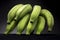 Closeup shot of a bunch of unripe green bananas with a black background