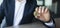 Closeup shot of businessman showing bitcoin, sitting at workplace in office, selective focus, panorama, copy space