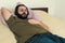 Closeup shot of a Caucasian beard man who lies in bed and listening to music on headphones