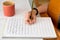 Closeup shot of a caucasian girl writing sheet music while holding a classical guitar