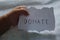 Closeup shot of a child hand holding a paper with a text donate