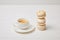 closeup shot of coffee cup and stack of macaroons on white wooden table