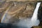 Closeup shot of the colorful and textured volcanic rocks with Haifoss waterfall and rainbow next to it. Porsadalur area in Iceland